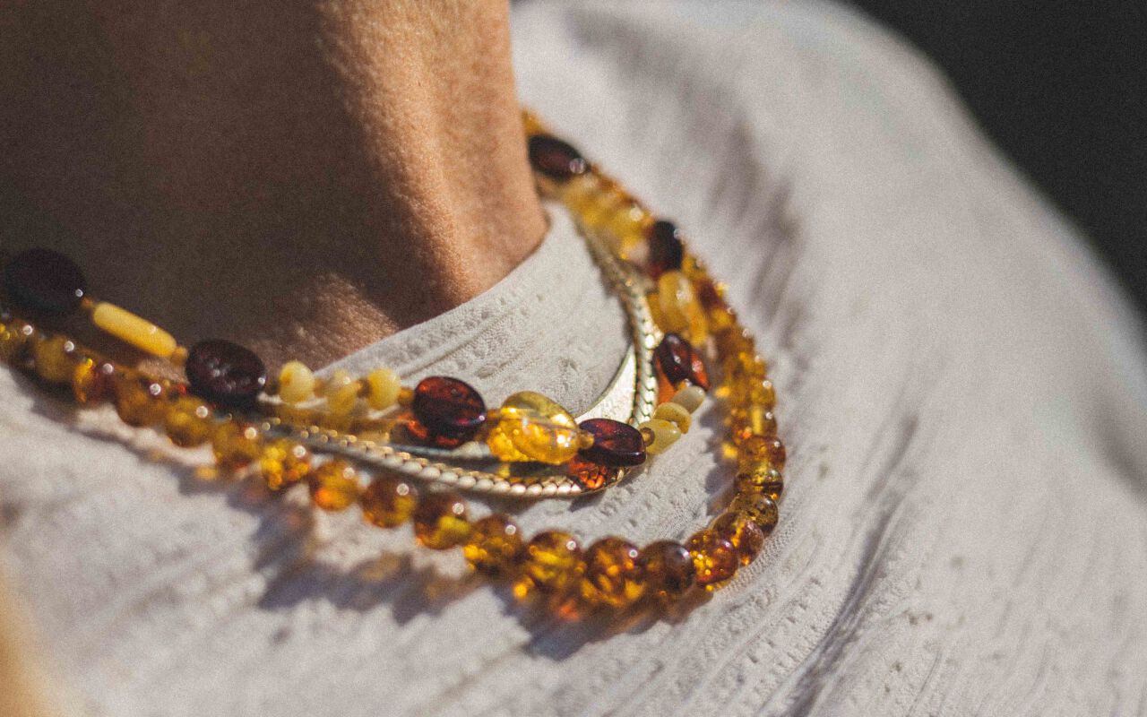 Naszyjnik w naturalnym ujęciu pokazany na szyi modelki z widoczną stylizacją i kolorowymi bursztynami.