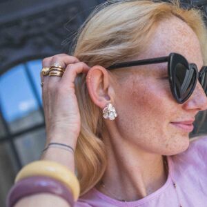 Kolczyki duże Miłokwiaty zaprezentowane w zbliżeniu na ucho projektantki biżuterii Matyldy Zielińskiej.