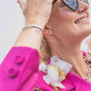 Profil twarzy z subtelnymi kolczykami kwiatkami, które dodają lekkości stylizacji.