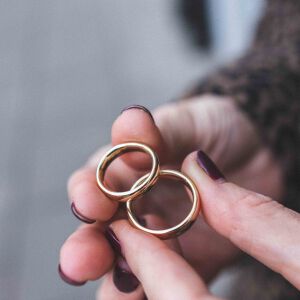 Zbliżenie na klasyczne obrączki o gładkiej powierzchni i owalnym profilu wykonane jako biżuteria minimalistyczna.