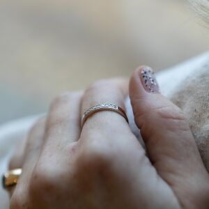 Złote obrączki z kamieniami ujęte w detalu na dłoni z widoczną strukturą metalu.
