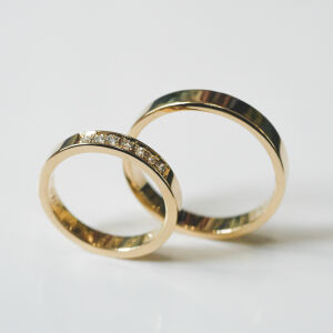 Zbliżenie na złote obrączki z kamieniami pokazujące strukturę metalu i osadzenie naturalnych kamieni.