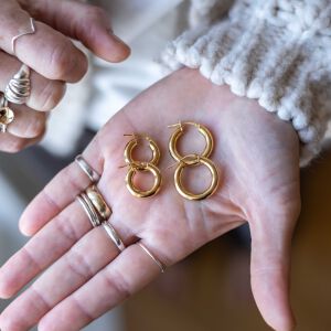 Kolczyki złote oponki pokazane na dłoni z widocznym detalem powierzchni.