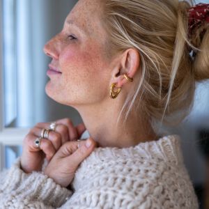 Kolczyki oponki pokazane na modelce w prostej stylizacji aby podkreślić ich złote wykończenie.