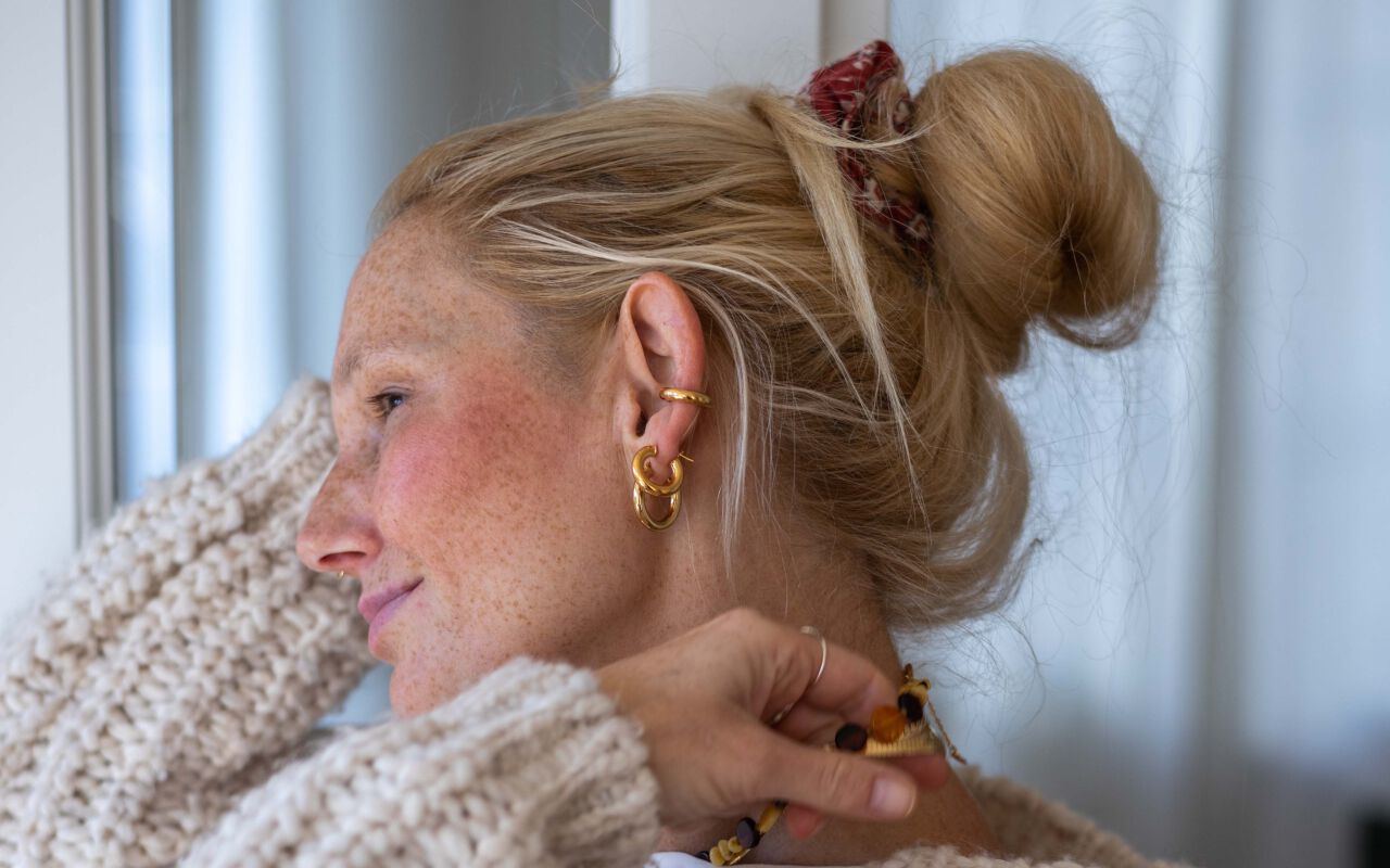 Kolczyki złote oponki widoczne na uchu modelki w naturalnym świetle.